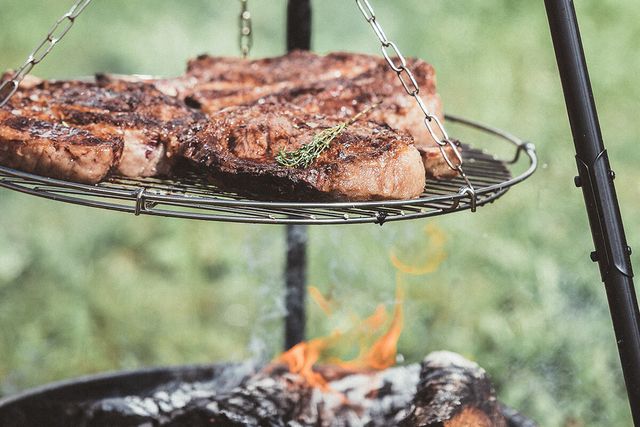 Steaks auf einem Schwenkgrill über offenem Feuer