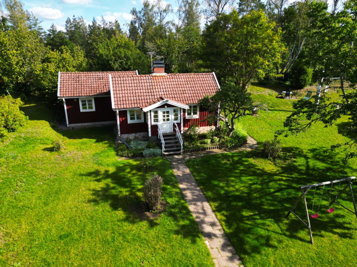 Das Trollhus von oben: rotes Holzhaus mit weißen Fenstern in einem großen grünen Garten
